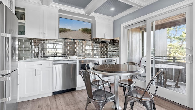 kitchen featuring white cabinets, appliances with stainless steel finishes, tasteful backsplash, and beamed ceiling