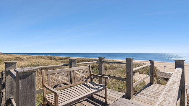 wooden deck featuring a water view and a beach view