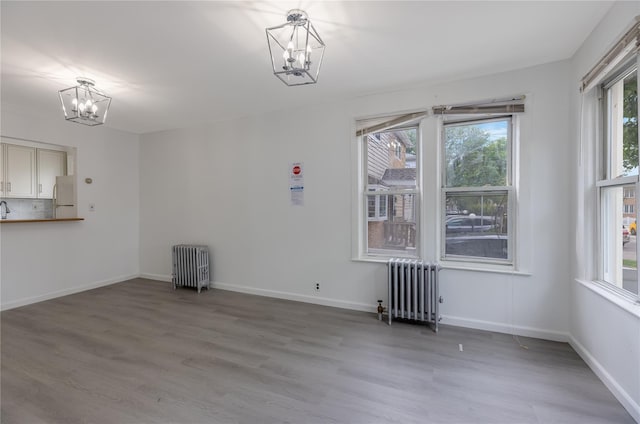 interior space featuring hardwood / wood-style floors, an inviting chandelier, and radiator