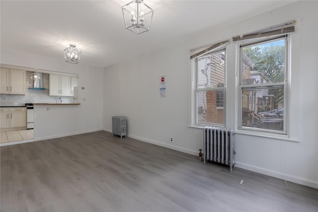 interior space featuring a chandelier, radiator heating unit, and light hardwood / wood-style flooring