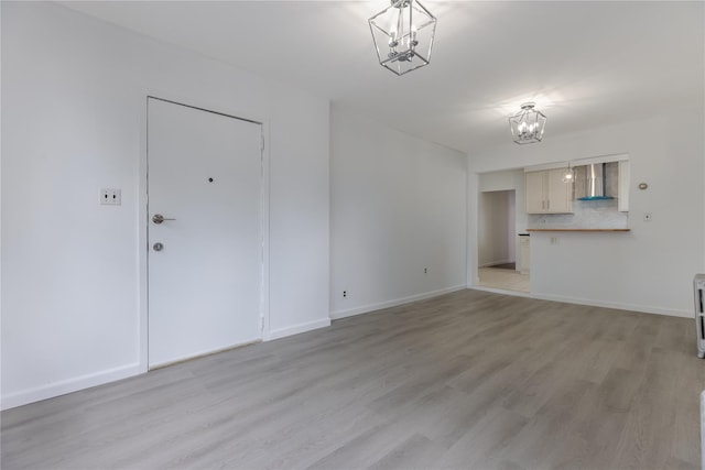 unfurnished living room with light hardwood / wood-style floors and an inviting chandelier