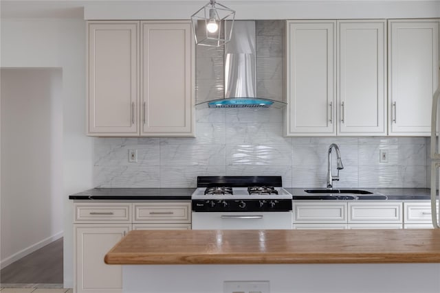 kitchen with wood counters, gas range gas stove, sink, wall chimney range hood, and decorative light fixtures