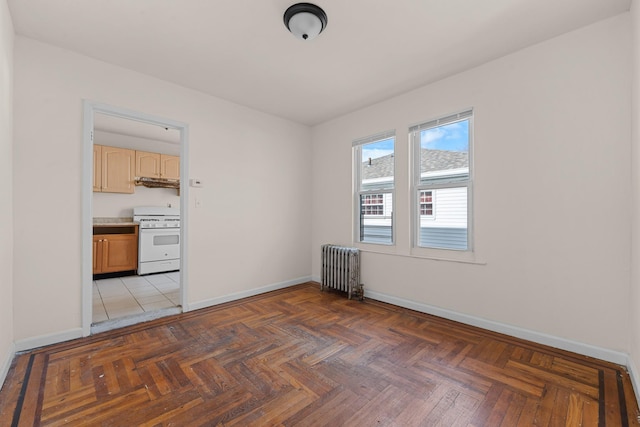 empty room with dark parquet flooring and radiator