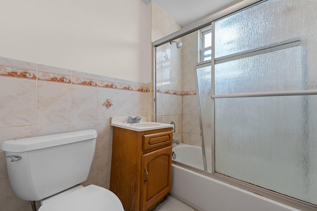 full bathroom with vanity, toilet, bath / shower combo with glass door, and tile walls