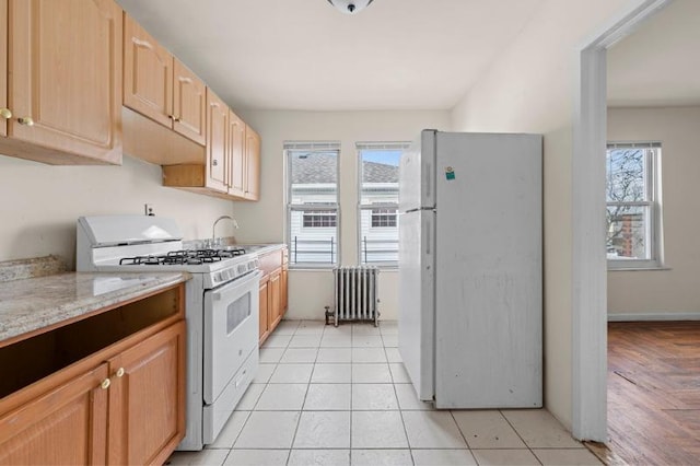 kitchen with radiator, a wealth of natural light, light brown cabinets, and white appliances