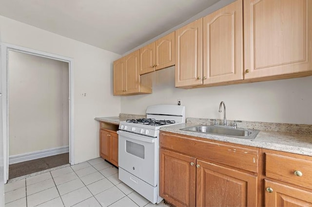 kitchen with light brown cabinets, white gas range, sink, and light tile patterned floors