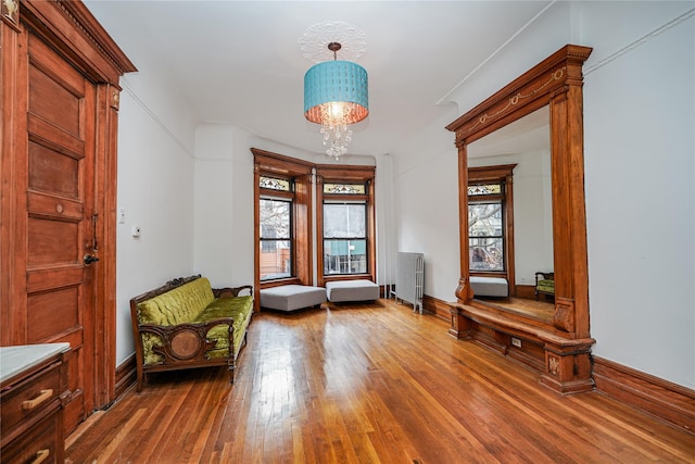 unfurnished room with radiator heating unit, a notable chandelier, a healthy amount of sunlight, and hardwood / wood-style floors