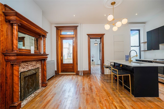 kitchen featuring radiator, a kitchen breakfast bar, sink, stainless steel range, and decorative light fixtures