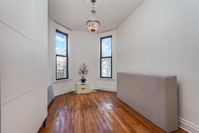 empty room featuring dark hardwood / wood-style floors, an inviting chandelier, and a wealth of natural light