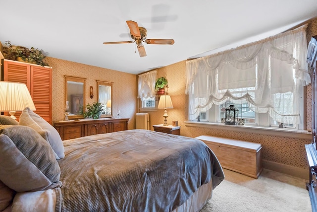 bedroom featuring ceiling fan, light carpet, and radiator