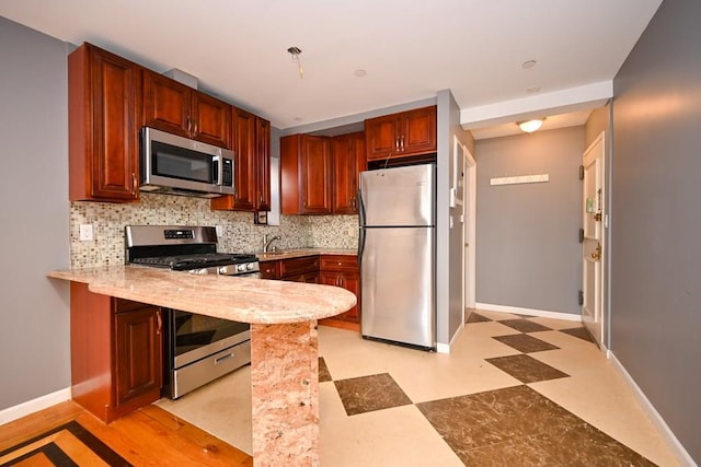 kitchen featuring sink, appliances with stainless steel finishes, tasteful backsplash, kitchen peninsula, and a breakfast bar area