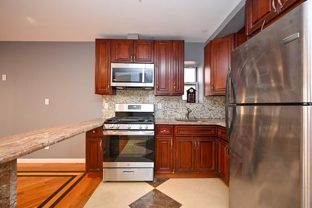 kitchen featuring backsplash, sink, light stone counters, and stainless steel appliances