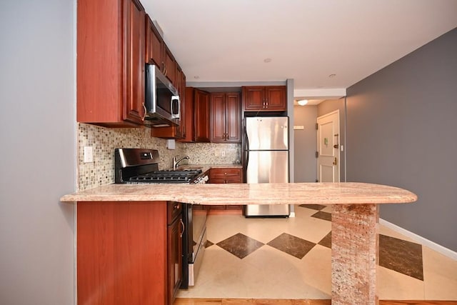 kitchen featuring kitchen peninsula, decorative backsplash, a breakfast bar, and appliances with stainless steel finishes