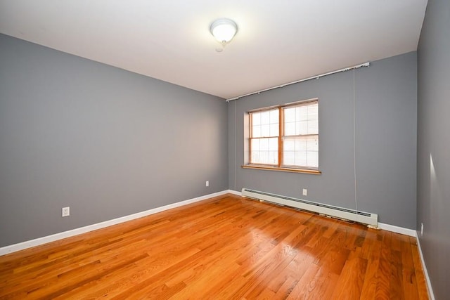 unfurnished room with hardwood / wood-style floors and a baseboard heating unit