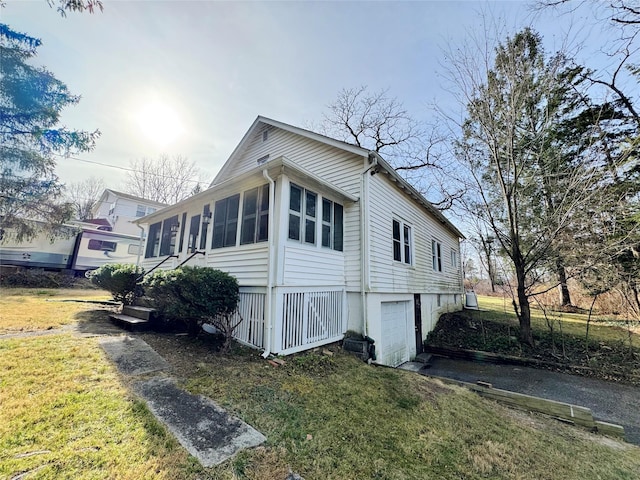 view of side of home featuring a yard, a garage, and a sunroom