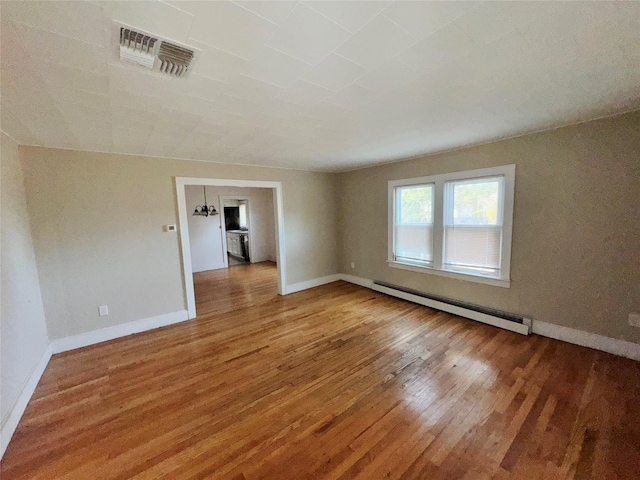 unfurnished room featuring hardwood / wood-style floors and a baseboard radiator