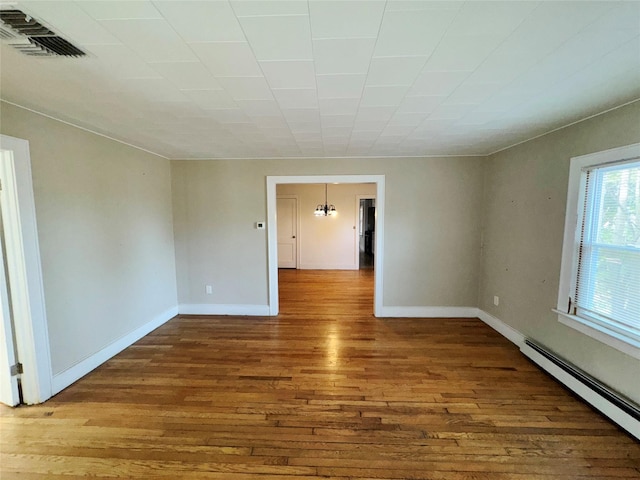 spare room featuring wood-type flooring and a baseboard radiator