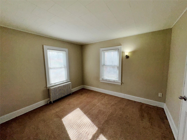 spare room featuring carpet, a healthy amount of sunlight, and radiator