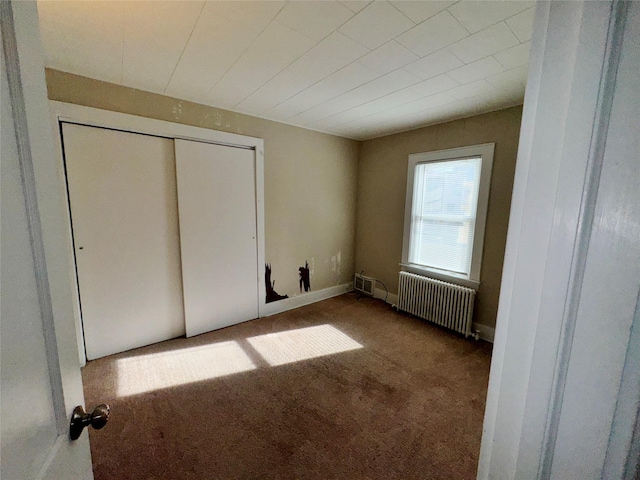 unfurnished bedroom featuring carpet floors, a closet, and radiator