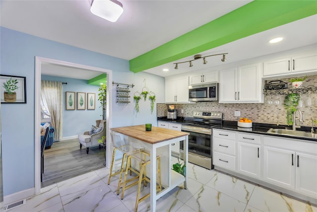 kitchen with backsplash, sink, white cabinetry, and stainless steel appliances