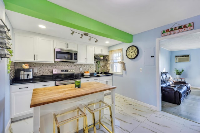 kitchen featuring wooden counters, stainless steel appliances, a wall mounted AC, sink, and white cabinetry