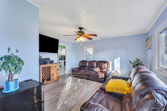 living room with hardwood / wood-style floors, a wall mounted air conditioner, crown molding, ceiling fan, and a textured ceiling