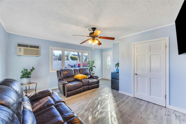 living room featuring crown molding, ceiling fan, light wood-type flooring, a textured ceiling, and a wall unit AC