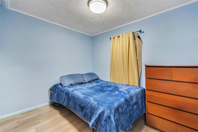 bedroom featuring light hardwood / wood-style floors, ornamental molding, and a textured ceiling