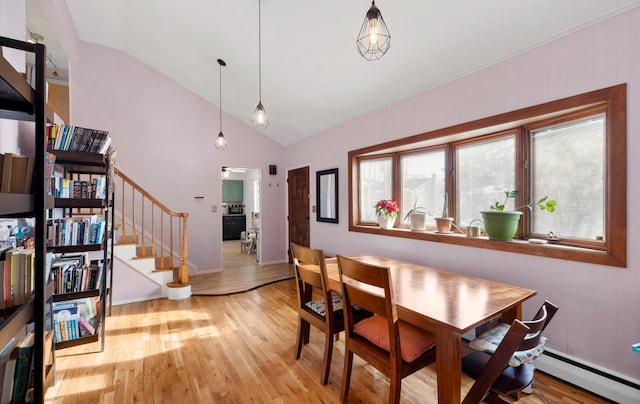 dining area featuring lofted ceiling, light hardwood / wood-style floors, and a baseboard heating unit