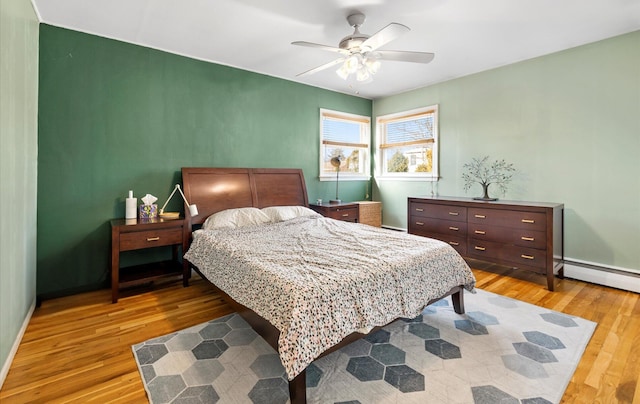 bedroom featuring ceiling fan, hardwood / wood-style floors, and a baseboard radiator