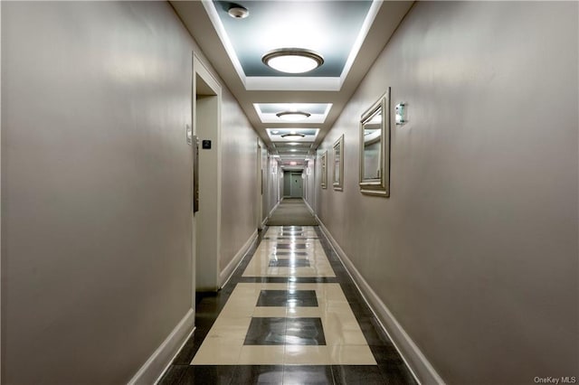 hall featuring tile patterned flooring and a tray ceiling