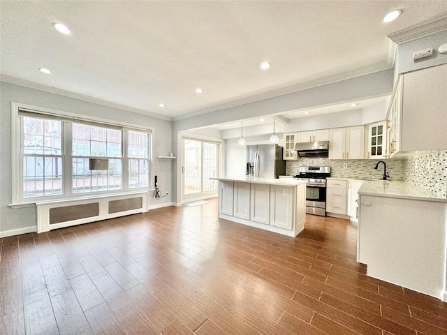 kitchen featuring radiator, a center island, decorative light fixtures, white cabinetry, and stainless steel appliances