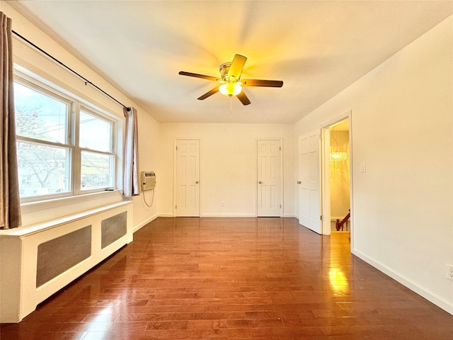 unfurnished room featuring ceiling fan, dark hardwood / wood-style flooring, and radiator heating unit