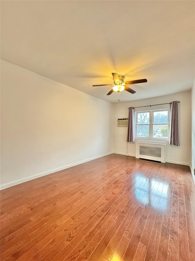 unfurnished room featuring ceiling fan, a wall mounted AC, and wood-type flooring