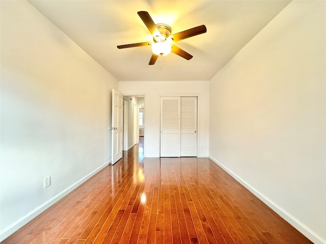 unfurnished bedroom with ceiling fan, a closet, and hardwood / wood-style flooring