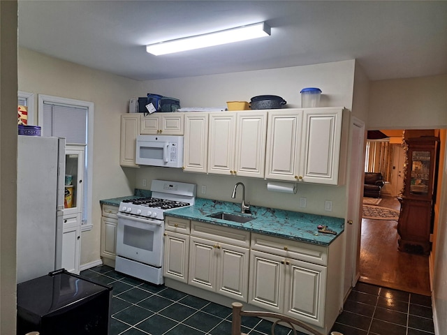 kitchen featuring white appliances, white cabinetry, dark tile patterned floors, and sink