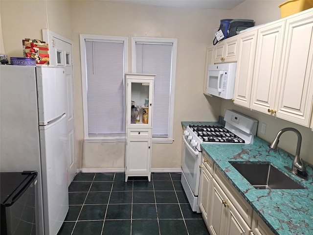 kitchen with light stone counters, white appliances, dark tile patterned floors, sink, and white cabinets