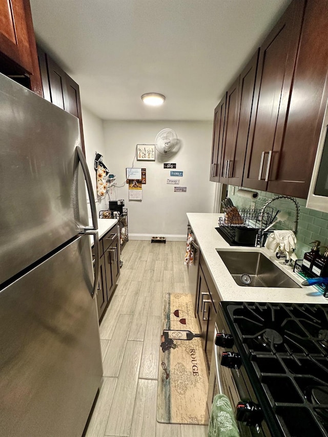 kitchen featuring sink, light hardwood / wood-style flooring, decorative backsplash, appliances with stainless steel finishes, and dark brown cabinets