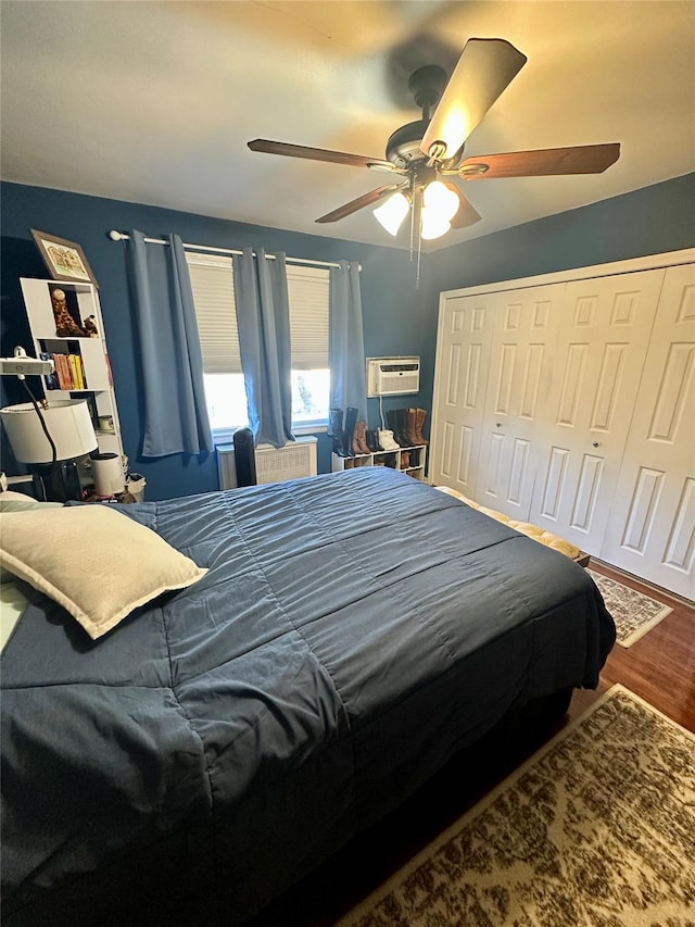 bedroom featuring hardwood / wood-style flooring, ceiling fan, a wall unit AC, and a closet