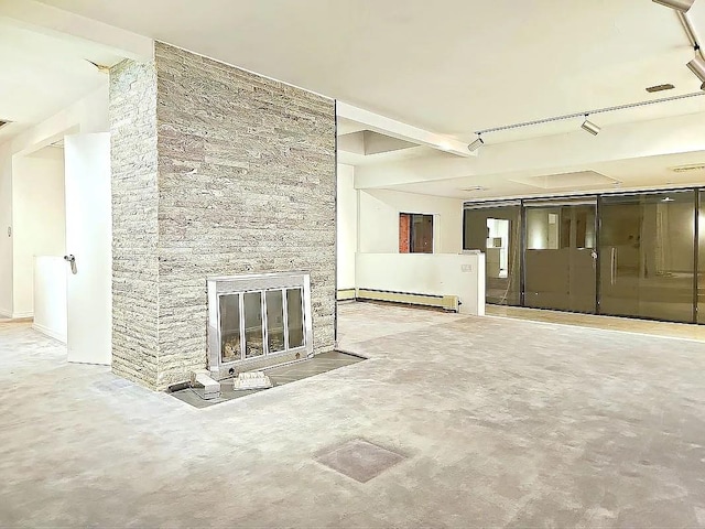 unfurnished living room with a stone fireplace, a baseboard radiator, and track lighting