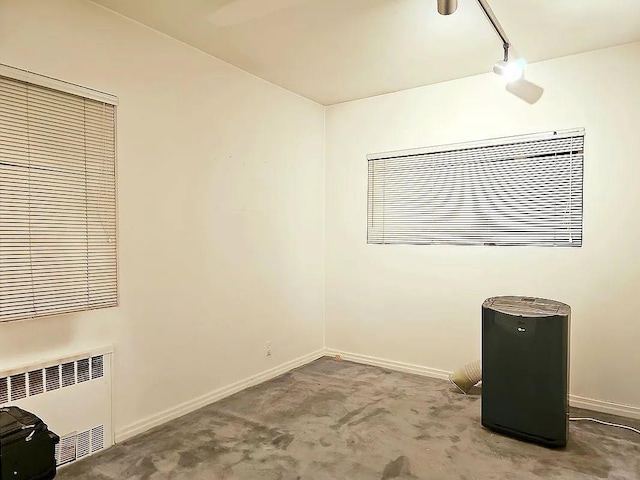 carpeted empty room with radiator and track lighting