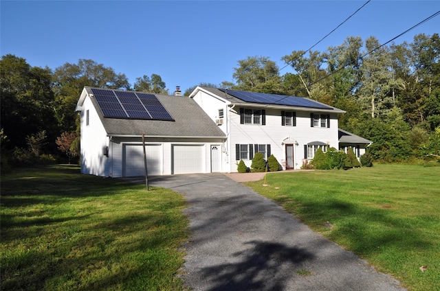 colonial inspired home featuring a front lawn, a garage, and solar panels