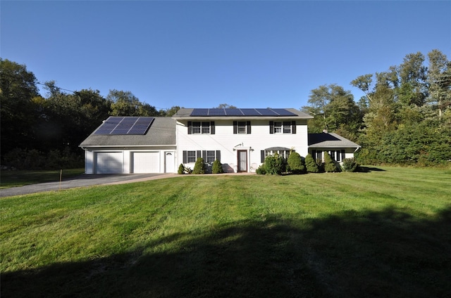 colonial home featuring a front lawn, a garage, and solar panels