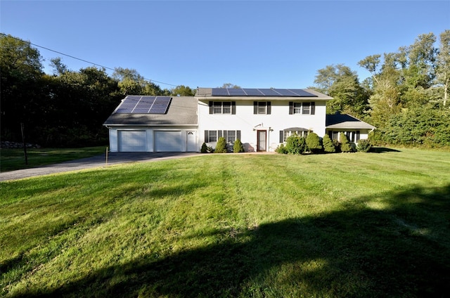 colonial-style house featuring a front yard, solar panels, and a garage