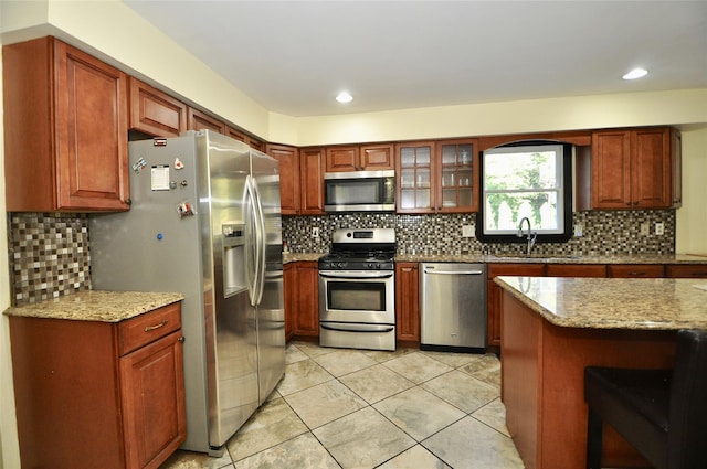 kitchen with sink, light stone counters, backsplash, light tile patterned floors, and appliances with stainless steel finishes