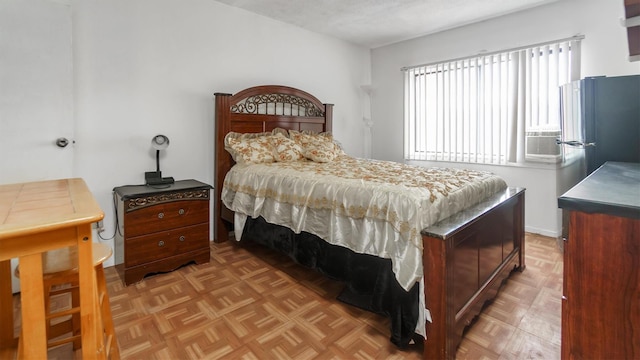 bedroom with a textured ceiling, stainless steel refrigerator, and light parquet floors