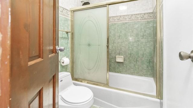 bathroom featuring toilet and combined bath / shower with glass door