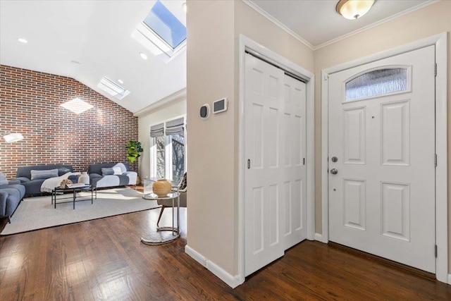 foyer entrance with dark hardwood / wood-style flooring, lofted ceiling with skylight, crown molding, and brick wall