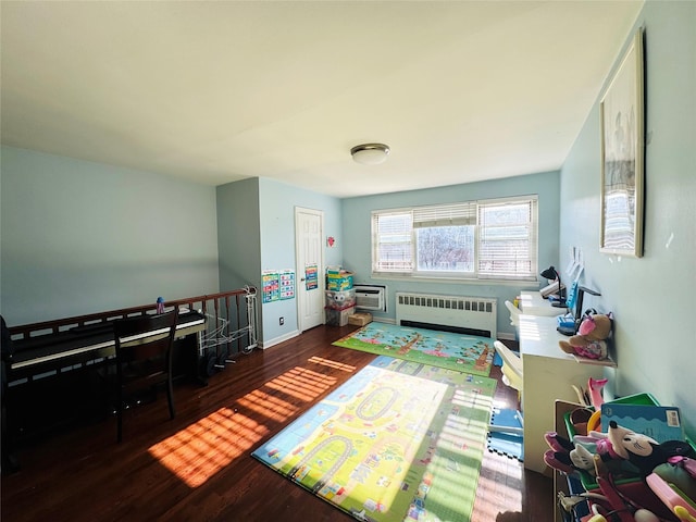 recreation room with radiator heating unit, an AC wall unit, and dark wood-type flooring