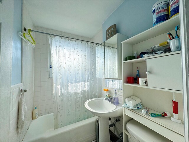 bathroom featuring toilet and shower / tub combo with curtain